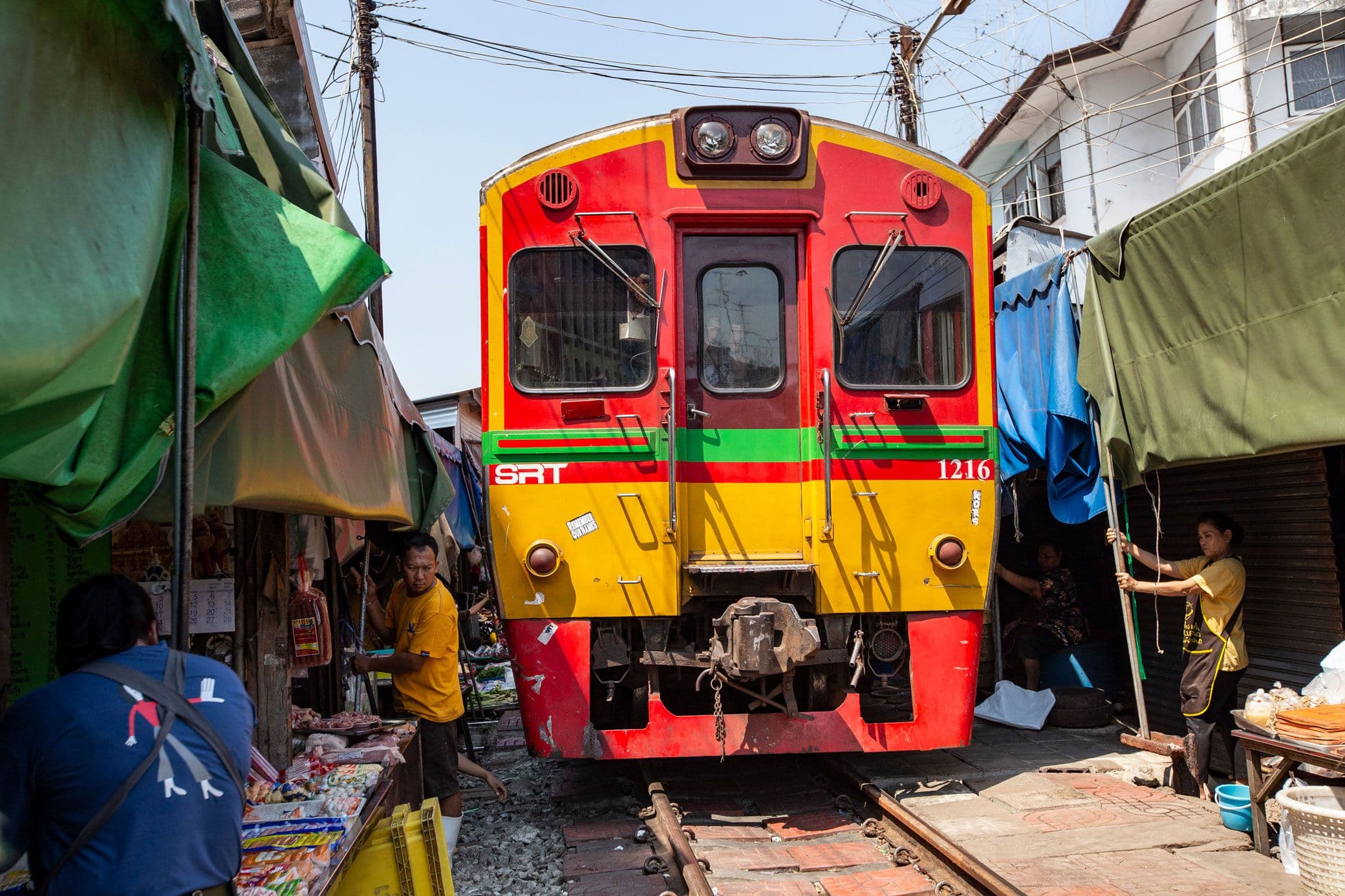 Train passing through Maeklong Railway Market in Thailand